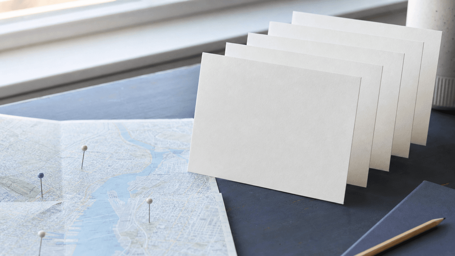 Blank postcards arranged beside a city map with location pins, representing account-based direct mail targeting.