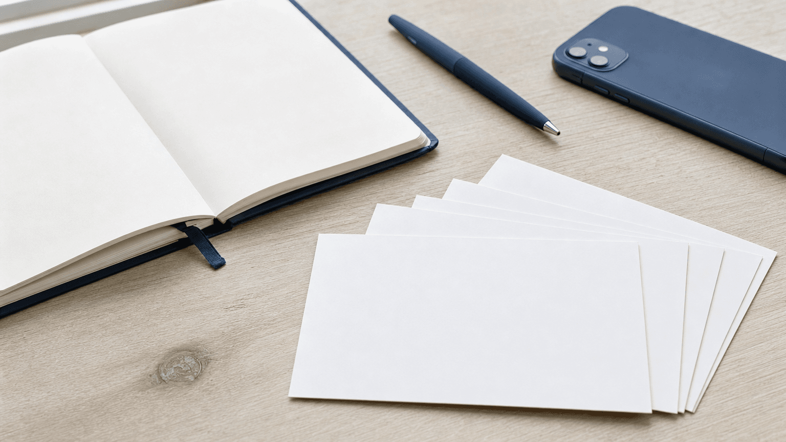 Blank business postcards fanned out on a desk with a notebook and pen, ready for a B2B lead generation mailer.